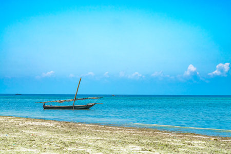 Fishing ship in water of Indian ocean on low tide. Zanzibar, Tanzania.の写真素材