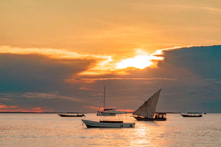 Fishing ship and boats in water of Indian ocean on a scenic sunset. Zanzibar, Tanzania.の写真素材