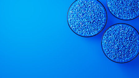 Top view on three glass cups with blue plastic polypropylene granules, masterbatch polymer grain, on...