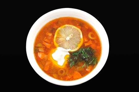 Soup with a lemon and olives close up on a black backgroundの写真素材