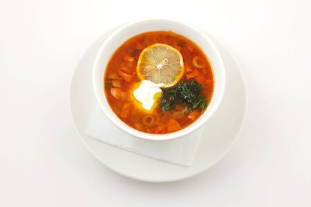 Soup with lemon and olives in a white plate on a white backgroundの写真素材