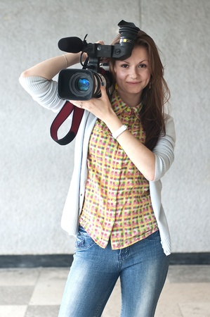 Portrait of the girl of the reporter with a videocamera with a direct sightの写真素材