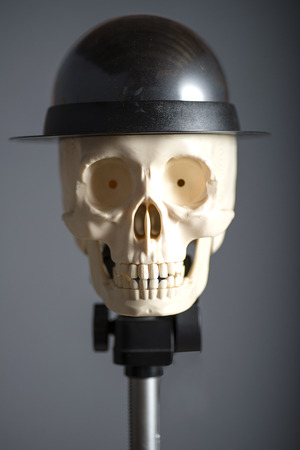 Skull in a hat on a support close up on a grey backgroundの写真素材