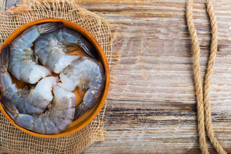 raw shrimp in a wooden plate on a textured board as a backgroundの写真素材