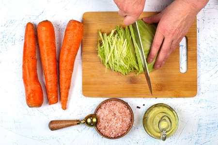 Carrots, salt, oil. The chef's hands are cutting the cabbage. view from above.の写真素材