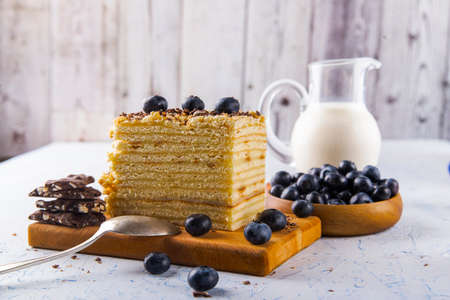 slice of cake with blueberries and a carafe of milk on a white tableの写真素材