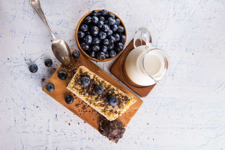 slice of cake with blueberries and a carafe of milk on a white table. view from aboveの写真素材