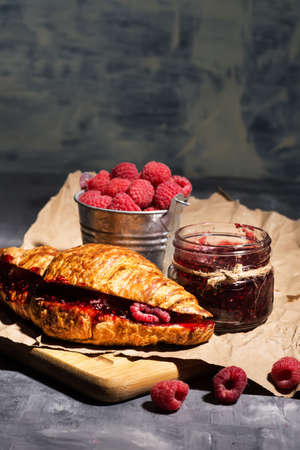 croissant with raspberry jam and raspberries on wrapping paper