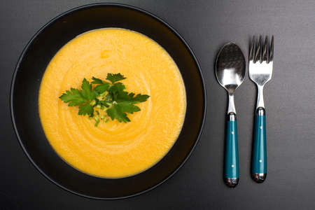 carrot puree soup in a black bowl on a black background. View from aboveの写真素材