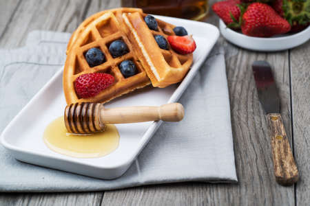 fresh waffles with blueberries and honey for breakfast. close-up