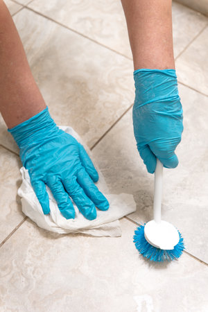 woman in gloves cleans the tiles with a brush on the floor in the bathroom.の写真素材