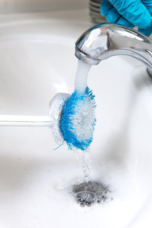 brush for washing dishes under running water. close-up.の写真素材