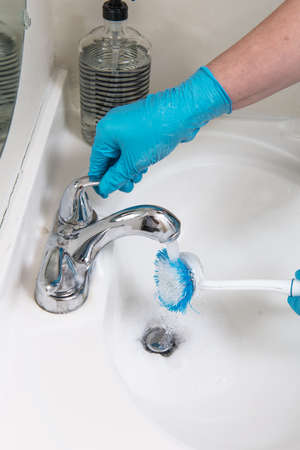 Gloved hands are cleaning the bathroom. Foam and brush close-up.の写真素材