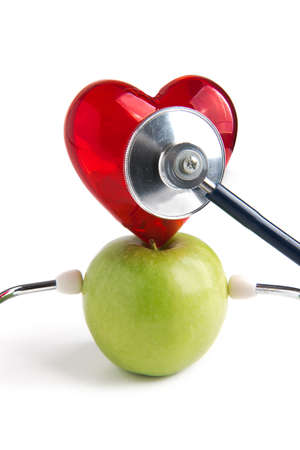 Medical stethoscope and heart on apple green isolated on white background. Healthy lifestyle and natural nutrition.の写真素材