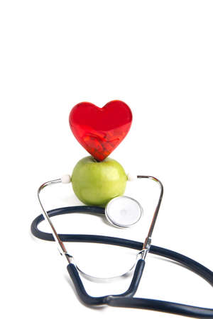 Medical stethoscope and heart standing on a green apple isolated on white background. Healthy lifestyle and natural nutritionの写真素材
