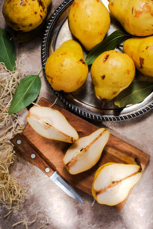 ripe yellow pears on a silver platter and a knife. view from above.の写真素材
