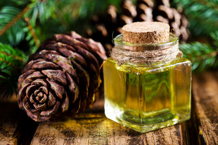 A bottle of Douglas fir essential oil with fresh Douglas fir branches in the backgroundの写真素材