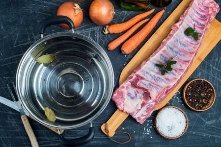 fresh meat and water in a saucepan on the kitchen table. Vegetables and spices for cooking broth.の写真素材