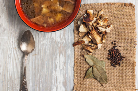 Mushroom soup with dried porcini mushrooms, bay leaf and pepper on rustic table texture background. view from above.の写真素材