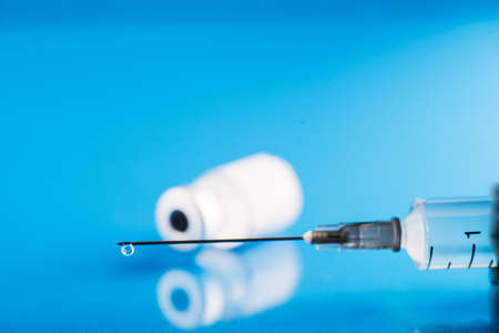 vial with Covid-19 vaccine and a syringe with a drop of vaccine on the needle. selective focus. copy text.の写真素材