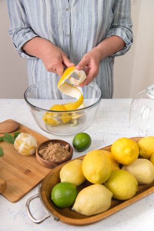 woman in the kitchen peels lemons for making lemonade.の写真素材