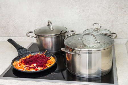 frying pan on a hot electric stove with chopped vegetables, beets, carrots, onions. Roast for making soup.の写真素材