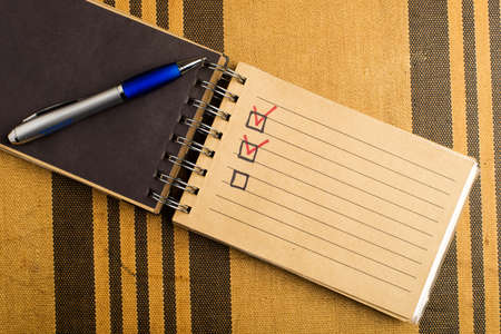 Yellow notebook with pen on a yellow striped background with a place for an inscription