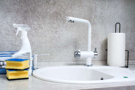 Modern kitchen sink and faucet. Detergents, washcloths and towels.