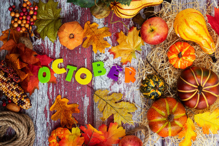 Colorful pumpkins and fallen leaves on a textured wooden dark background. The inscription OCTOBER. view from above. Space for text.の写真素材