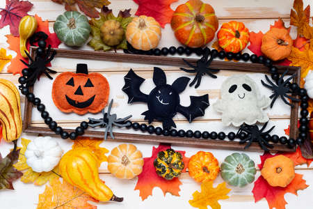 pumpkins and autumn leaves on a white table. halloween dolls frame.