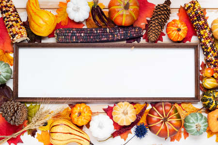 Autumn composition of pumpkins, corn and fallen leaves. Thanksgiving holiday concept. Photo frame and autumn leaves. top view, copy spaceの写真素材