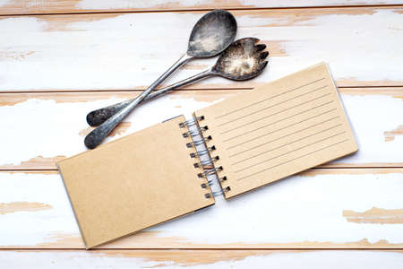 Blank recipe book and vintage spoon, top view. blank notepad for recipe on white board table. Place for textの写真素材