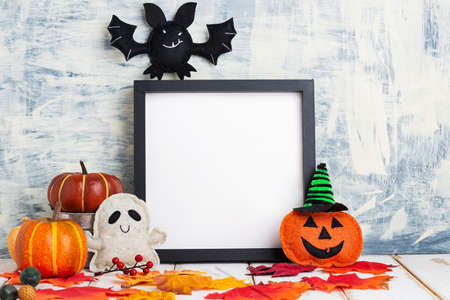 Halloween holiday concept with empty black frame, pumpkins and bat on a light table against a gray wall. copyspace,の写真素材