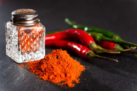 bunch of red peppers, capsicum and pepper pot on a black table. close-up. selective focus. Space for text.の写真素材