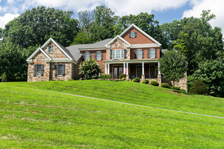 Leesburg. Virginia. USA. August 15, 2022. Large country brick house and summer landscape with a perfect lawn. Blue sky and white clouds.のeditorial素材