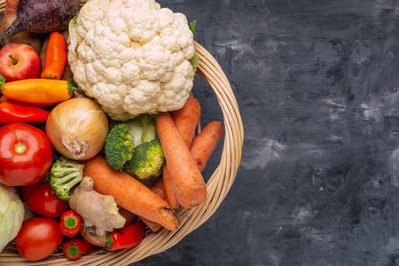 basket full of vegetables and fruits stands on a gray floor, top view. Autumn and harvest time. Space for text.の写真素材