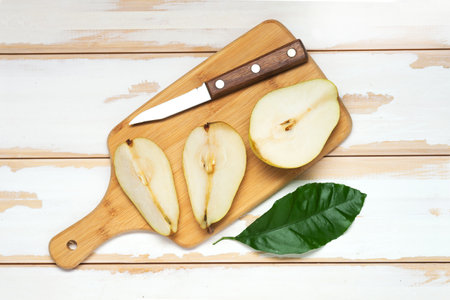 slices of pears on a cutting board with knife. White boards, top view.の写真素材