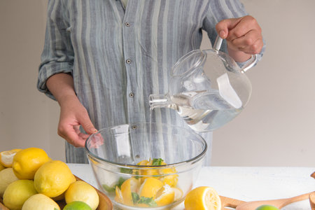 woman make homemade lemonade with fresh yellow lemons and green mint. close-up photo