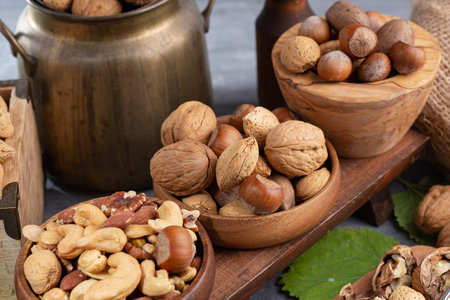 nuts of different varieties in a wooden bowls and nut cracker on gray table. Close-up. selective focus.の写真素材