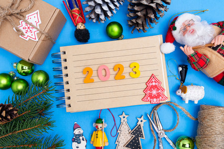 Christmas composition from New Year's toys, fir branches, gift box and notepad with space for text. on a blue background. view from above.の写真素材