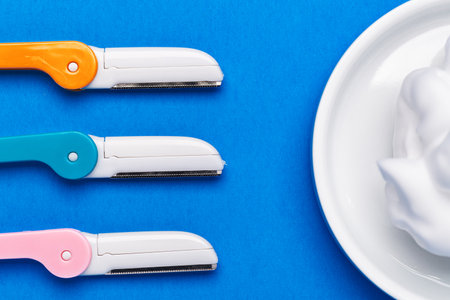 beautiful multicolored razor shavers. Colored razors shavers, on a blue background and shaving foam. copy space for text. view from above.の写真素材