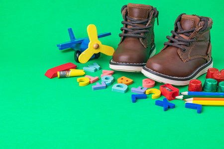 Children's boots for a boy on a green background. toy, Pencils, colored letters and candies. Space for text.の写真素材