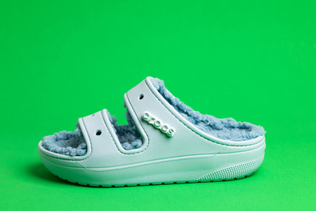 Crocs blue rubber sandals with faux fur lining, on a green background.のeditorial素材