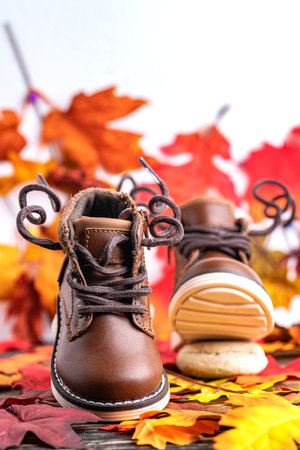 children's brown boots for boy, against the background of autumn leaves. Space for text..の写真素材