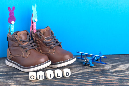Baby shoes and toys on wooden floor near blue wall. Childhood concept. Copy space for text. The inscription CHILD from cubes.の写真素材