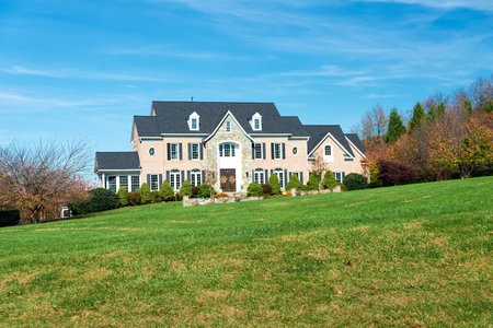 exterior view of luxury house with yellow trees. beautiful autumn landscape. Yard with green grass.のeditorial素材