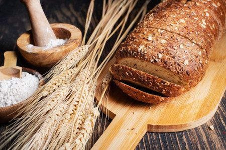 loaf of rye bread, ears of wheat and a bowl of flour. close-up.