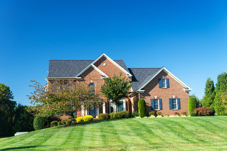 Luxurious large single family brick house with large green lawn. landscape on an autumn day.のeditorial素材