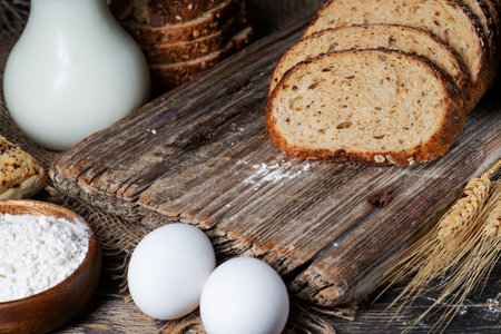 slices of rye bread, ears of wheat, eggs and a bowl of flour. close-up.