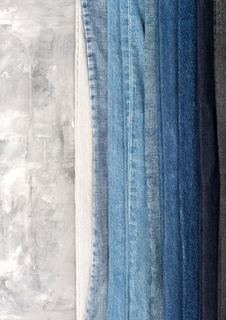 Stack of different jeans on gray background. Space for text.の写真素材